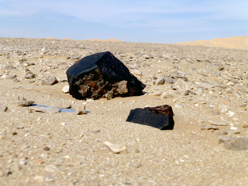 Das Bild zeigt einen Meteorit in der Wüste.