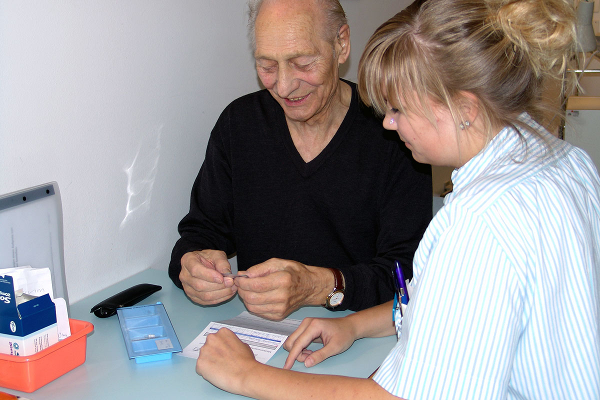 Das Symbolbild zeigt die persönliche Gesundheitsberatung einer älteren Person durch eine speziell ausgebildete Pflegefachperson.