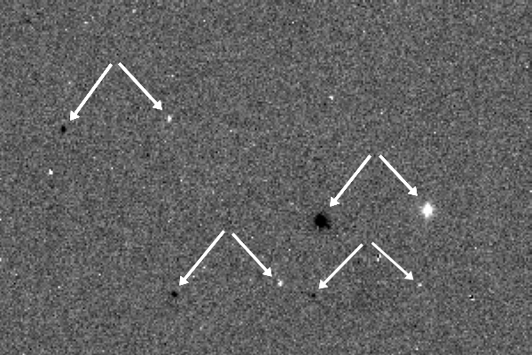Das Bild zeigt zwei übereinanderlappende Aufnahmen: die markierten hellen und dunklen Punkte sind Positiv-, respektive Negativaufnahmen von Sternen.