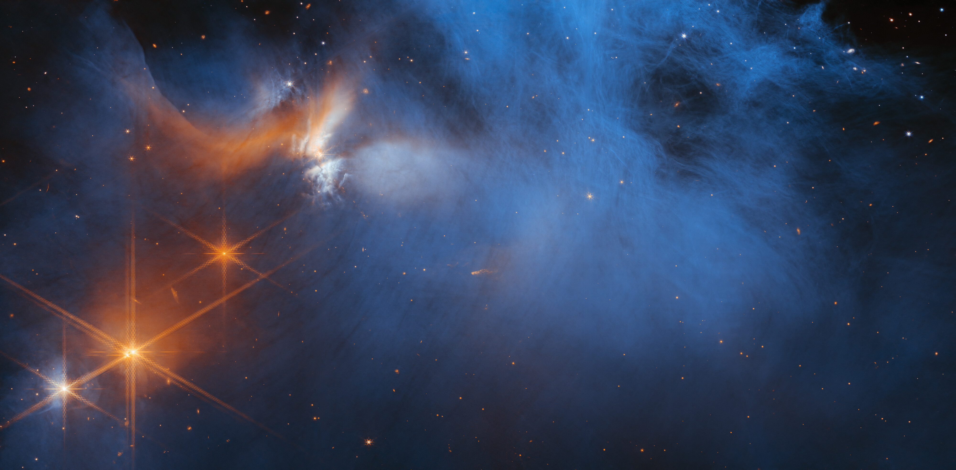 Dieses Bild der Nah-Infrarot-Kamera (NIRCam) des James Webb-Weltraumteleskops der NASA/ESA/CSA zeigt die zentrale Region der dunklen Molekülwolke Chameleon I. Die Lichter der zahlreichen Hintergrundsterne sind als orangefarbene Punkte hinter der Wolke zu erkennen. © NASA, ESA, CSA, und M. Zamani (ESA/Webb)