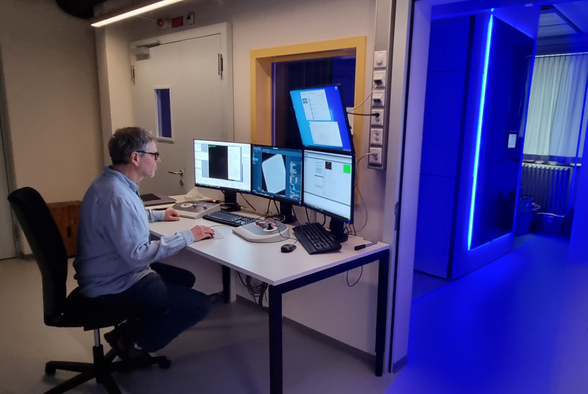 PD Dr. Jean-Marc Jeckelmann, Ko-Autor der Studie, bei der Aufnahme von Bildern mit dem neuen Kryo-Elektronenmikroskop (das blau beleuchtete Gerät im Hintergrund). © IBMM / Universität Bern