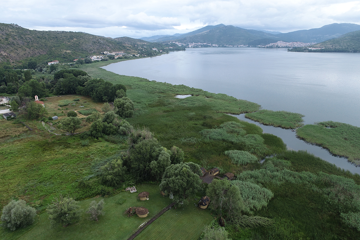 Die prähistorische Fundstelle von Dispilio befindet sich am Kastoria-See in Nordgriechenland. Im Hintergrund ist die Stadt Kastoria zu sehen. Unten, in der Bildmitte, steht die moderne Rekonstruktion eines prähistorischen Pfahlbaus. © Universität Bern, Bild: Marco Hostettler