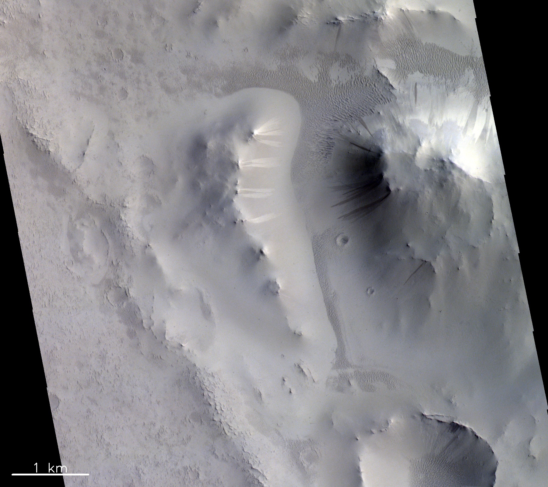 Dieses Bild zeigt markante helle und dunkle Streifen an Hängen in der Region Locras Vallis auf dem Mars. Der genaue Zusammenhang zwischen diesen Streifen wird noch diskutiert, aber die führende Theorie legt nahe, dass sie durch trockene Lawinenprozesse gebildet werden.   © ESA/Roscosmos/CaSSIS, CC BY-SA 3.0 IGO