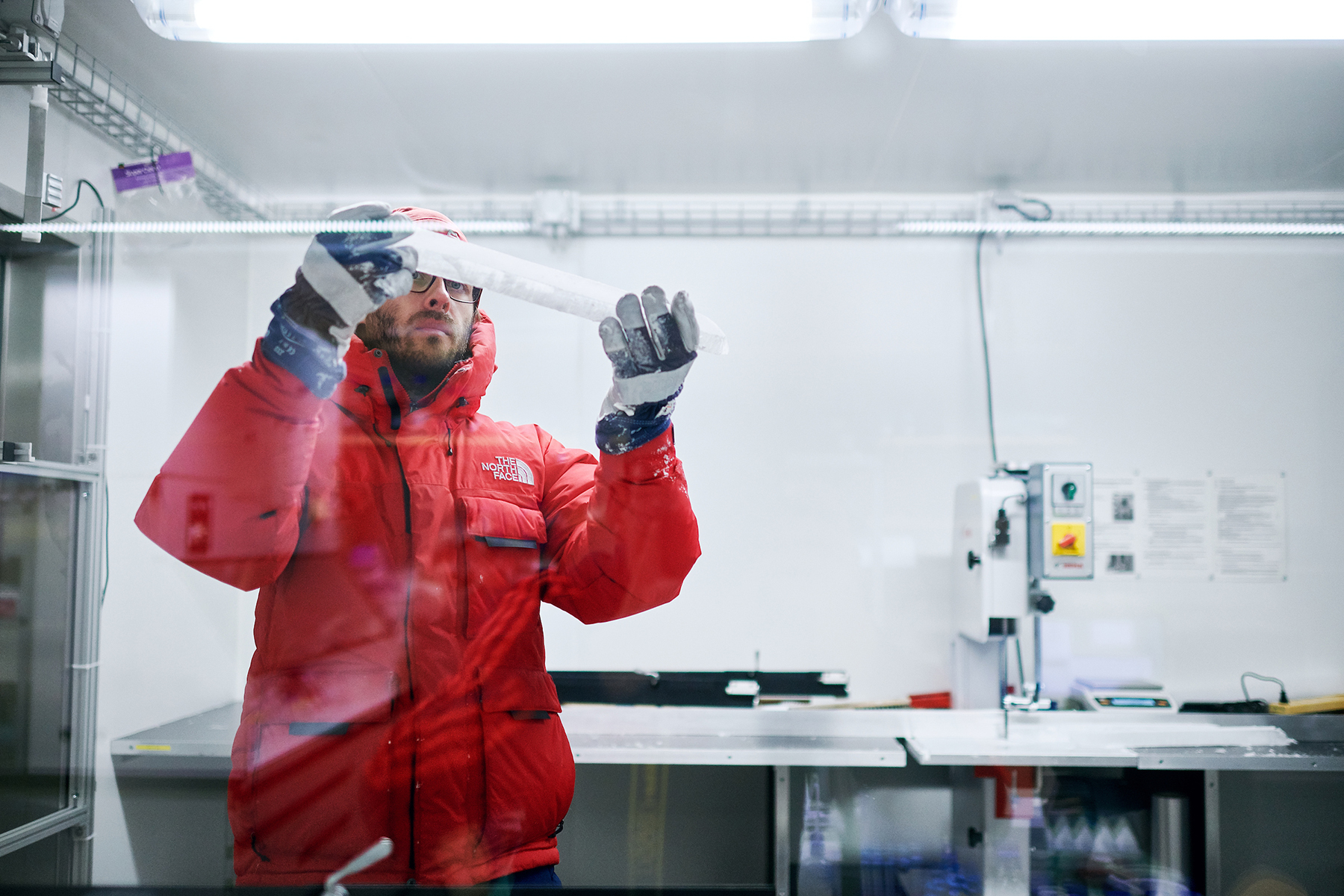 Ein Berner Forscher inspiziert ein Segment eines Eiskerns im Tiefkühl-Labor der Universität Bern. © Universität Bern, Manu Friederich